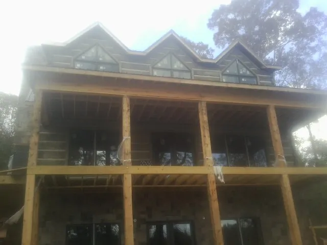 Dormers and porch framing on a large log home under construction — Roof Coating work by our crew in Hassell