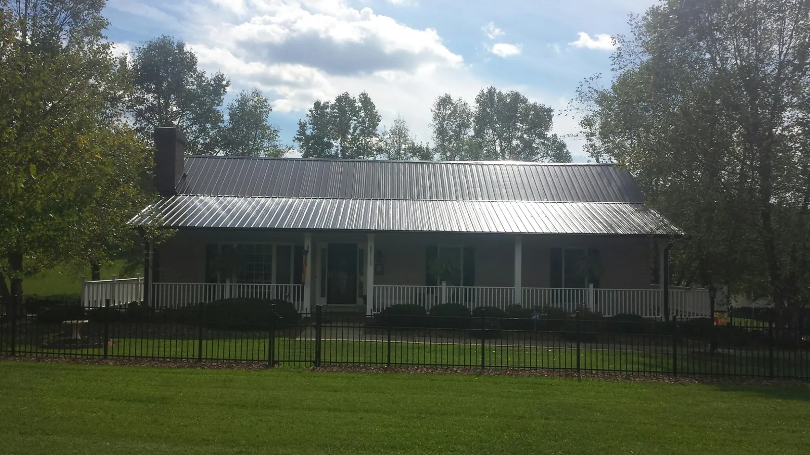 Gray metal roof on a brick ranch with a full width front porch — Gutter Guard Installation work by our crew in Hassell