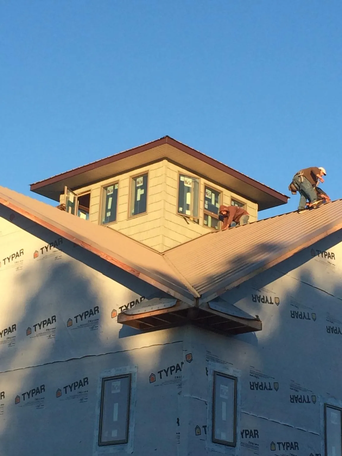Roofers working around a rooftop cupola on a new metal roof at sunset — Roof Waterproofing in Hassell by Roofing Brothers